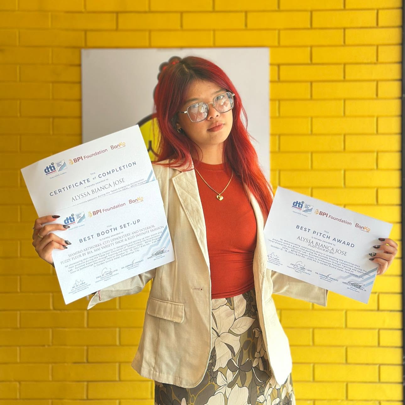 Alyssa holding her SEAL to BETA certificates, including the Best Pitch Award